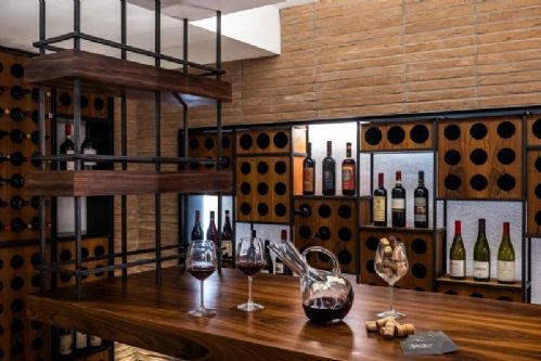 Wine room in Brianza con parete in mattoni, tavolo in noce e portabottiglie in legno — Winest